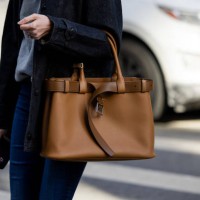 Guest wears brown Prada bag outside Calvin Klein on February 07, 2025 in New York City.