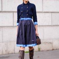 Guest wears brown sunglasses, a blue knitted jacket, a blue Miu Miu midi skirt, brown leather Miu Miu bag, brown boots, outside Miu Miu, during the...