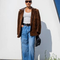 Guest wears brown wild leather jacket, black bag, denim jeans outside Munthe during day four of the Copenhagen Fashion Week SS25 on August 08, 2024...