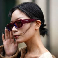 Guest wears burgundy squared sunglasses from Prada, a beige heart-neck / cut-out chest / short tube jumpsuit, a brown shiny leather and sheep fur...