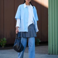 Guest wears clear green sunglasses, silver chain necklace, white long sleeve shirt, light blue short sleeve unbuttoned shirt, navy blue pleated mini...
