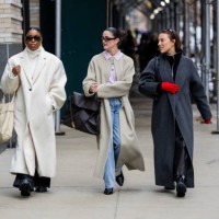 Guest wears creme white oversized coat & a guest black bag, coat & a guest wears grey coat, red gloves outside Ulla Johnson during New York Fashion...