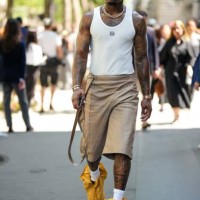 Guest wears cross pendant silver earrings, silver rhinestones necklaces, a white tank-top from Loewe, brown wrap shiny leather knees shorts, a gold...