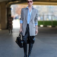 Guest wears dark brown aviator sunglasses, gold earrings, light blue oversized half buttoned long sleeve shirt, light gray white pinstripe double...