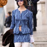 Guest wears dark brown bob hair, dark blue sunglasses, navy blue pattern knit buttoned cardigan jacket, navy blue pattern knit mini skirt, white long...
