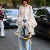 Guest wears dark brown fluffy headband, gold necklace, dark brown sunglasses, white sheer mesh high neck flowy long sleeve Chloe shirt, dark gray...