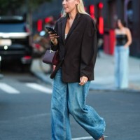 Guest wears dark brown oversized blazer jacket, dark brown Tory Burch leather handbag, gold rings, gold bracelets, washed light blue denim jean...