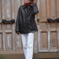 Guest wears dark brown sunglasses, bright red turtle neck long sleeve shirt, shiny black oversized jacket, dark brown leather gloves, white pants,...