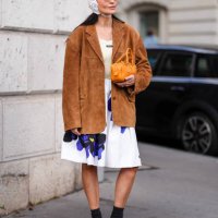 Guest wears dark brown sunglasses, white textured cap, dark brown suede oversized Miu Miu blazer jacket, cream tank top, white loose purple floral...