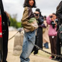 Guest wears dark green dark brown leather jacket, light green light gray clutch leather bag, washed denim jean baggy pants, light gray brown fluffy...