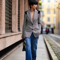 Guest wears earrings, a black and white houndstooth pattern oversized blazer jacket, a black crocodile pattern leather bag, blue denim jeans / pants,...