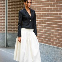 Guest wears earrings, a black Spencer jacket, a white gathered midi skirt, black leather moccasins, outside Fendi, during the Milan Fashion Week -...