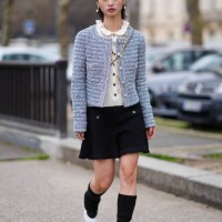 Guest wears earrings, a white pullover with ruffled collar, a pastel pale striped tweed jacket , a black mini skirt , knee high socks, white shoes,...
