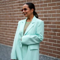 Guest wears Fendi sunglasses, earrings, a green fishnet top, an oversized light green jacket, a red leather Fendi bag , outside Fendi, during the...