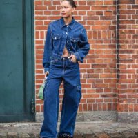 Guest wears gold earrings, a navy blue denim buttoned jacket, matching navy blue denim cargo large pants, a green matte leather handbag, dark brown...