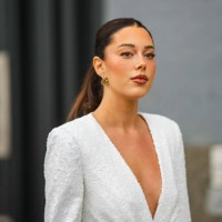 Guest wears gold earrings, a white embroidered sequined V-neck / shoulder-pads / blazer jacket, during New York Fashion Week, on September 11, 2022...
