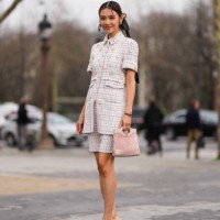 Guest wears gold earrings, dark brown braided hair with black bow, light pink pattern/print short sleeve buttoned light pink embellished Chanel...