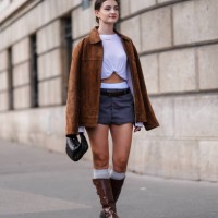 Guest wears gold earrings, white long sleeve cropped shirt, white briefs, dark gray mini skirt, dark brown oversized suede blazer jacket, shiny black...