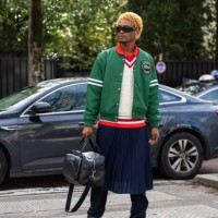 Guest wears green college jacket, blue skirt, black bag outside Lacoste during the Womenswear Fall/Winter 2024/2025 as part of Paris Fashion Week on...