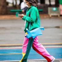 Guest wears green jacket, multicolor pants , white sneakers, blue dog-shaped bag at Sao Paulo Fashion Week 2024 N58 - Street Style at Parque...