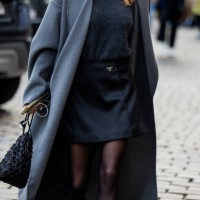 Guest wears grey coat, black Prada skirt, tights, knit outside Nicklas Skovgaard during the Copenhagen Fashion Week AW24 on January 29, 2024 in...