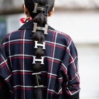 Guest wears Hermes silver hair accessories and a blue, red and white checked coat outside Hermes show during Womenswear Spring/Summer 2025 as part of...