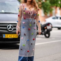 Guest wears light brown sunglasses, gold chain necklace with gold heart pendants, white sheer mesh long sleeve midi dress with red brown blue green...