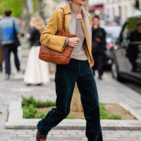 Guest wears light gray t-shirt, light gray cropped jacket, dark yellow cardigan sweater, dark yellow leather cropped jacket, shiny dark brown leather...