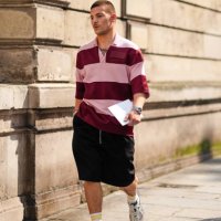Guest wears light pink and dark red striped oversized shirt, a watch, a gold bracelet, a silver bracelet, black shorts, white with yellow striped...