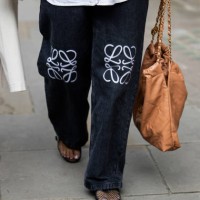 Guest wears Loewe jeans, Chanel bag in brown outside Simone Rocha during London Fashion Week September 2024 on September 15, 2024 in London, England.