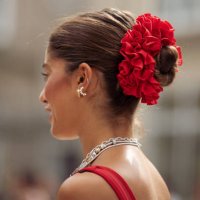 Guest wears long red sheer maxi dress, black bag, silver layered necklaces, red scrunchy for hair is seen outside the Gestuz show during day four of...