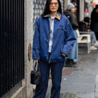 Guest wears Miu Miu blue jacket, striped jeans, black bag outside Magliano during the Milan Fashion Week Menswear Fall/Winter 2025-2026 on January...