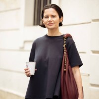 Guest wears navy blue T-shirt, dark blue denim skirt, burgundy bag outside the Loewe presentation during the Womenswear Fall/Winter 2025/2026 as part...