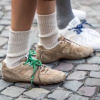 Guest wears New Balance brown sneakers, white socks outside Miu Miu during the Womenswear Fall/Winter 2025/2026 as part of Paris Fashion Week on...