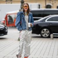 Guest wears orange sunglasses, a gray wool pullover, a blue denim jacket, a white with purple / orange / green print pattern shoulder bag from...