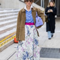 Guest wears purple bag, skirt with graphic print, blue blouse, brown suede jacket outside Carolina Herrera during New York Fashion Week on February...