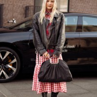 Guest wears red and white checkered dress, black and white pointy shoes, black bag, brown leather jacket, knitted hat outside A. Roege Hove show...