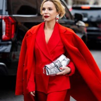 Guest wears red blazer, coat, silver bag, pants outside Michael Kors during New York Fashion Week on February 11, 2025 in New York City.