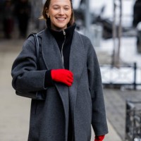 Guest wears red gloves, grey coat outside Ulla Johnson during New York Fashion Week on February 09, 2025 in New York City.