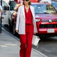 Guest wears red suit, white blazer, bag outside Carolina Herrera on September 12, 2023 in New York City.