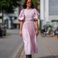 Guest wears red sunglasses, light pink puffy sleeve midi dress, silver rings, black boots leather shoes, outside Won Hundred, during the Copenhagen...