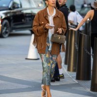 Guest wears Savette bag, brown fringed wild leather jacket outside Michael Kors during New York Fashion Week on September 10, 2024 in New York City.