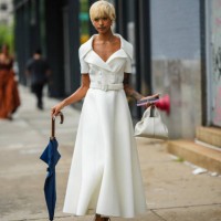 Guest wears silver and rhinestones earrings, a matching silver and rhinestones necklace, a white latte short sleeves / buttoned / belted / long felt...
