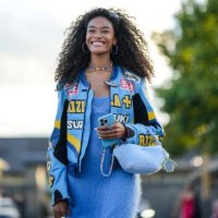 Guest wears silver earrings, a multicolored crystals necklace, a blue wool long dress, a blue shiny leather with yellow and white embroidered pattern...
