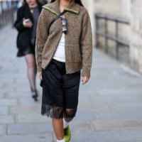 Guest wears silver earrings, dark brown pattern oversized unzipped cardigan jacket, white top, black sunglasses in top, shiny black crossbody leather...