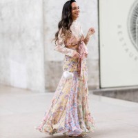 Guest wears silver heeled sandals, a white heart shaped bag and a floral long sleeved flounced long dress outside Zimmermann show during Womenswear...