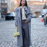 Guest wears silver hoop earrings, light pale yellow buttoned up long sleeve shirt, gray blazer jacket, light gray trench coat, light yellow leather...