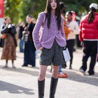 Guest wears silver necklaces, light pink black pattern tweed Chanel jacket blazer, black white pattern tweed shorts, shiny black heeled leather...