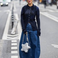 Guest wears star shaped Chanel bag, wide leg dark blue denim jeans, button up knit outside Akris during the Womenswear Fall/Winter 2024/2025 as part...