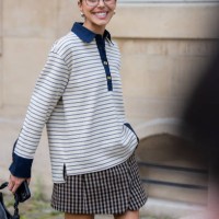 Guest wears striped polo shirt with long sleeves, skirt, bag, glasses outside Ganni during the Womenswear Fall/Winter 2025/2026 as part of Paris...